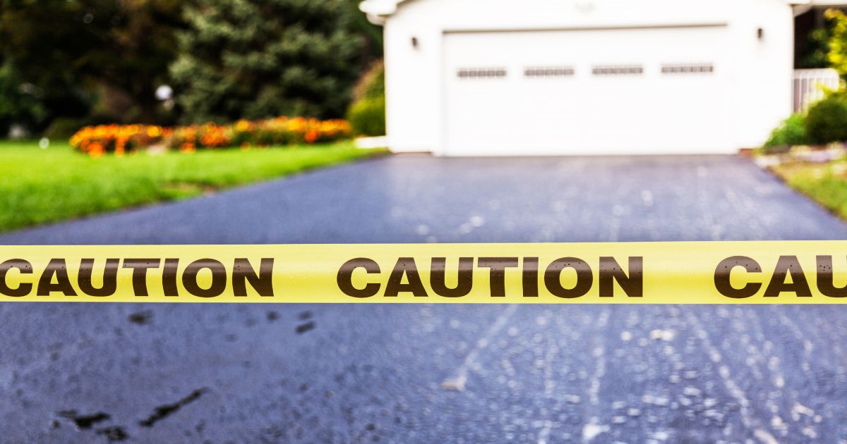 Caution tape across asphalt driveway