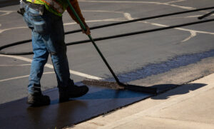 Worker using a sealcoating brush during asphalt resurfacing