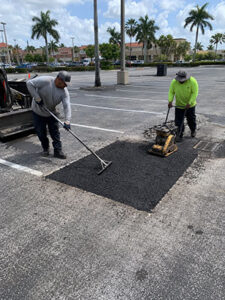 Trinity Asphalt Paving crew completing a localized asphalt patch repair in a Delray Beach parking lot.