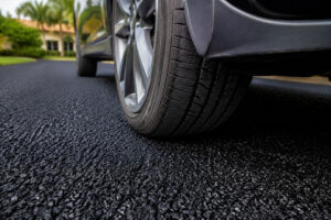 Close-up of a car’s front tire resting on a new asphalt driveway in South Florida