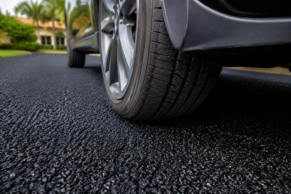 Close-up of a car’s front tire resting on a new asphalt driveway in South Florida