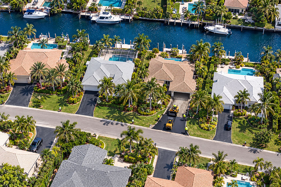 Aerial view of a Palm Beach Gardens neighborhood with a Trinity Asphalt crew paving a new driveway.